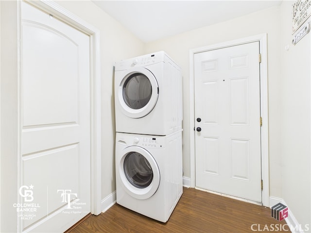 laundry area featuring stacked washer and dryer, baseboards, dark wood finished floors, and laundry area