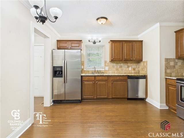 kitchen with appliances with stainless steel finishes, a sink, a chandelier, tasteful backsplash, and dark wood-style floors