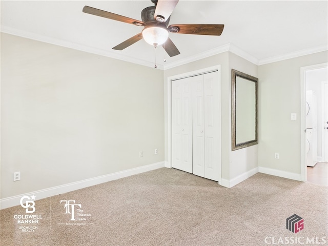 unfurnished bedroom with crown molding, carpet floors, baseboards, and stacked washer and dryer