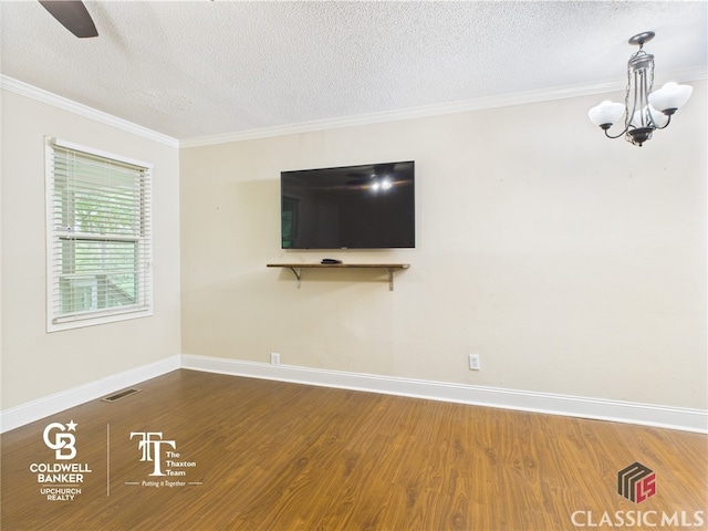 unfurnished living room with visible vents, ornamental molding, wood finished floors, baseboards, and a textured ceiling
