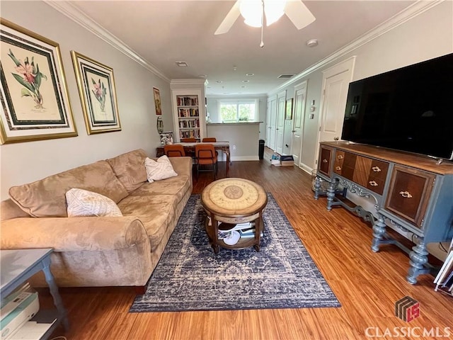 living room featuring crown molding, a ceiling fan, baseboards, and wood finished floors