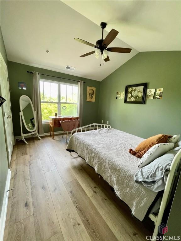 bedroom with visible vents, ceiling fan, lofted ceiling, and hardwood / wood-style floors
