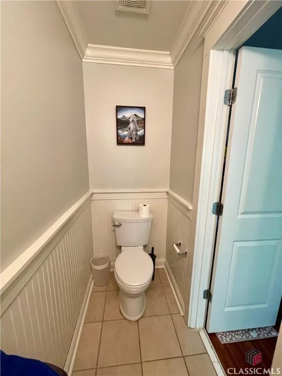 bathroom featuring crown molding, toilet, tile patterned flooring, and a wainscoted wall