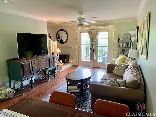 living room with crown molding, a ceiling fan, baseboards, and wood finished floors