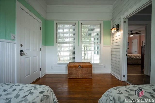 bedroom featuring crown molding, a wainscoted wall, and wood finished floors