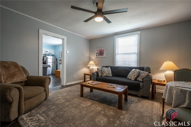 living room featuring crown molding, a ceiling fan, baseboards, and wood finished floors