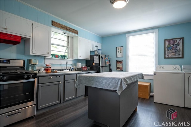 kitchen with independent washer and dryer, a sink, dark wood finished floors, stainless steel appliances, and a wealth of natural light
