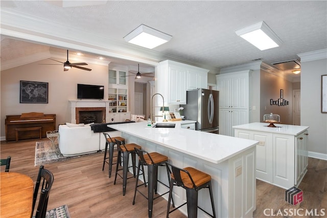 kitchen with freestanding refrigerator, wood finished floors, a kitchen island, ceiling fan, and a sink