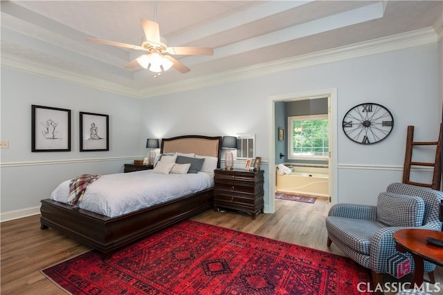 bedroom with crown molding, a tray ceiling, baseboards, and wood finished floors