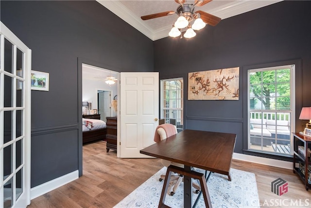 office area with light wood-type flooring, ornamental molding, a towering ceiling, and a ceiling fan