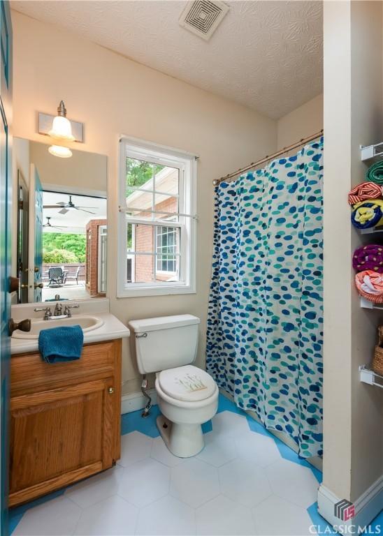 full bath with vanity, toilet, a textured ceiling, a shower with shower curtain, and visible vents