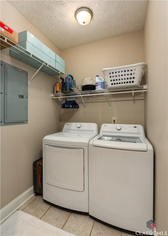 clothes washing area with light tile patterned floors, laundry area, washing machine and dryer, and electric panel