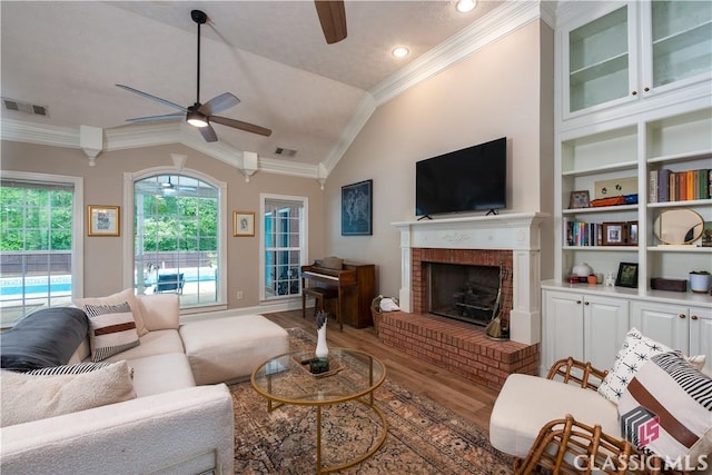living room with crown molding, a ceiling fan, wood finished floors, vaulted ceiling, and visible vents