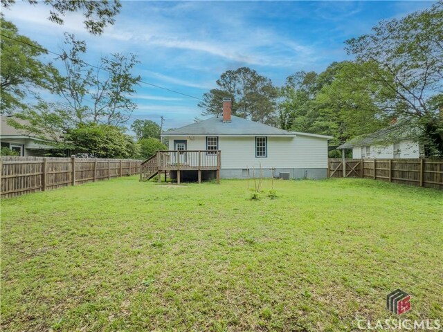 1114 S Broad St, Monroe, GA 30655 - rear view of property featuring a lawn, a wooden deck, a fenced backyard, and a chimney