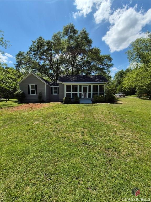 back of house featuring a lawn and a sunroom