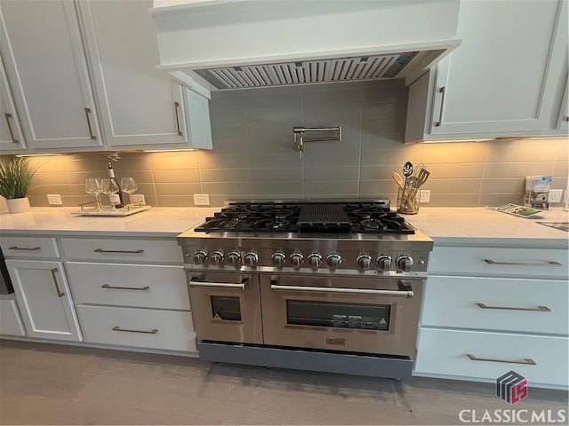 1200 Askew Trl, Greensboro, GA 30642 - kitchen with range with two ovens, custom range hood, tasteful backsplash, and white cabinets