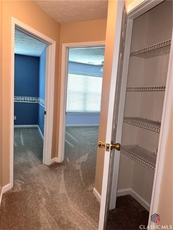 hall featuring carpet flooring, a textured ceiling, and baseboards