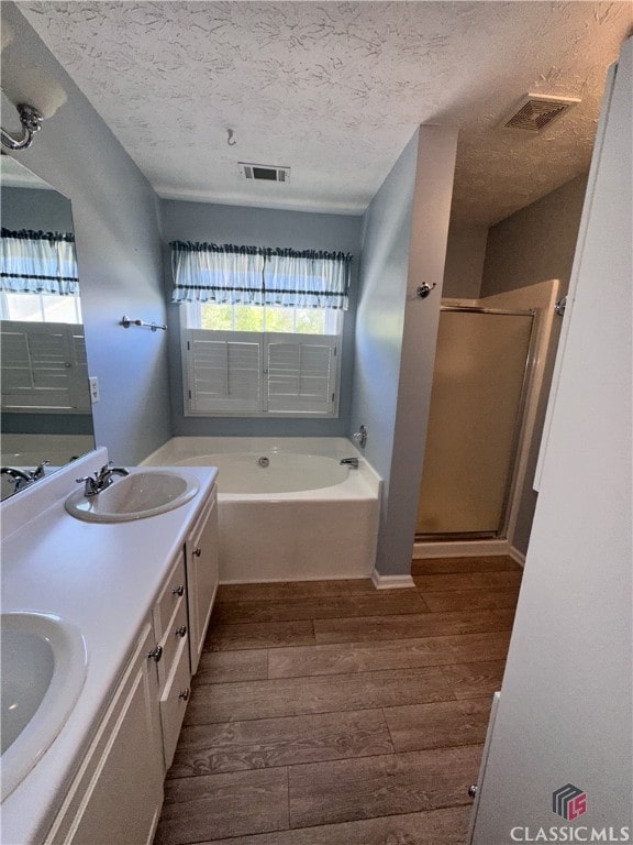 full bathroom with visible vents, a sink, wood finished floors, and a stall shower
