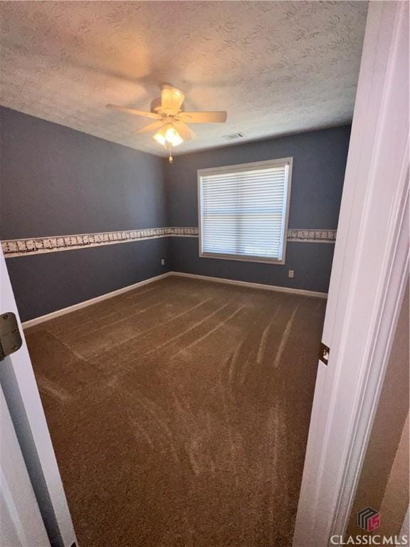 empty room featuring ceiling fan, a textured ceiling, visible vents, baseboards, and carpet flooring