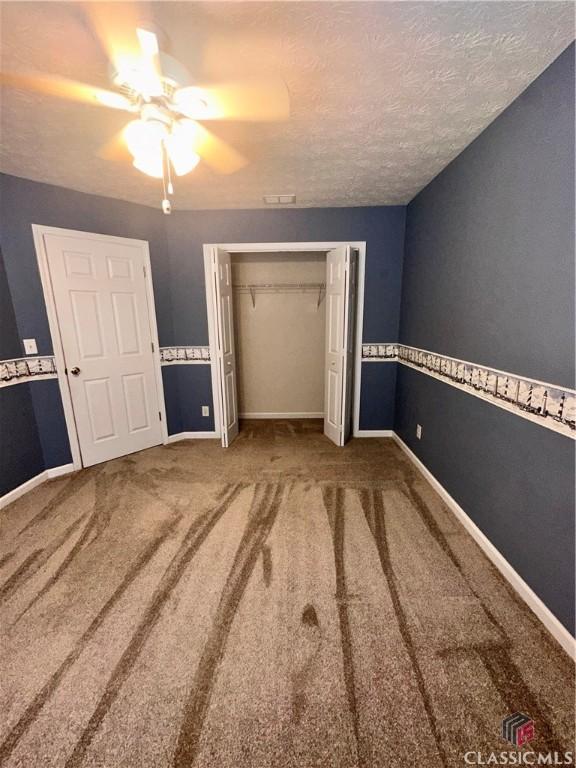 unfurnished bedroom with baseboards, carpet, and a closet