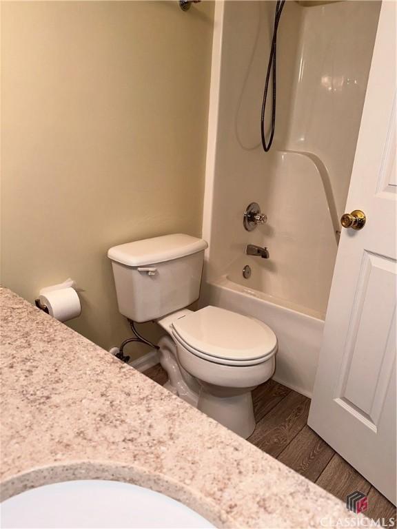 bathroom featuring bathing tub / shower combination, toilet, and wood finished floors