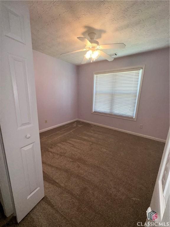 unfurnished room featuring a ceiling fan, a textured ceiling, baseboards, and dark colored carpet