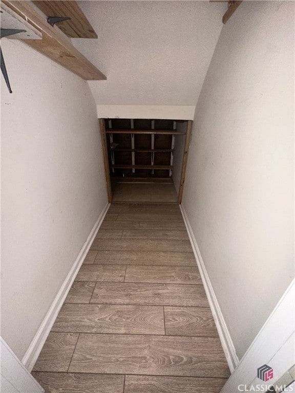 corridor featuring a textured ceiling and wood finished floors