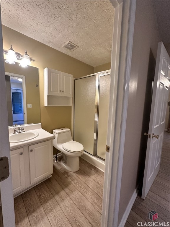 full bath featuring vanity, a stall shower, wood finished floors, and visible vents