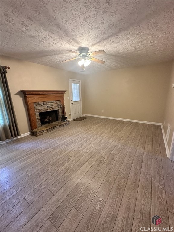 unfurnished living room featuring baseboards, a ceiling fan, a textured ceiling, and wood finished floors