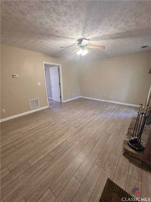 unfurnished living room featuring visible vents, a ceiling fan, a textured ceiling, and wood finished floors