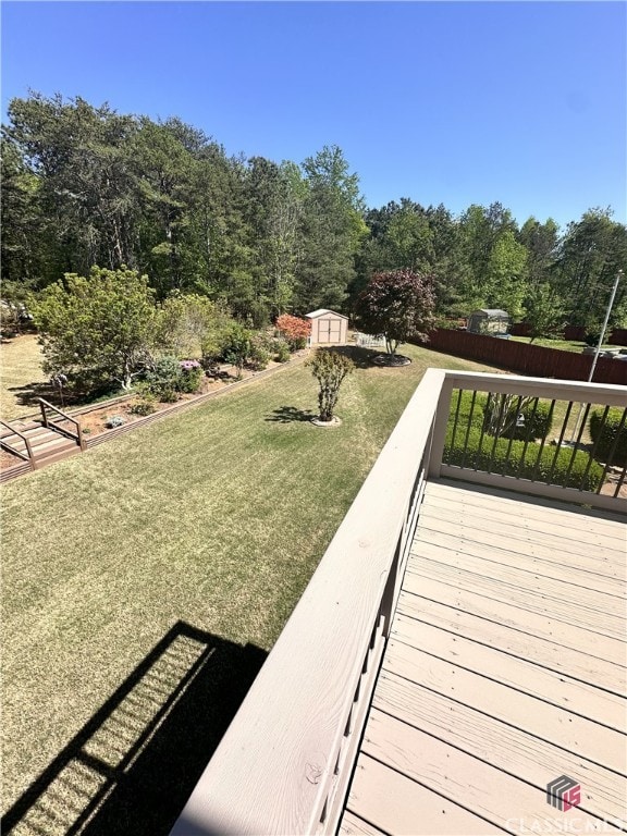view of home's community with an outdoor structure, a deck, a yard, and a shed