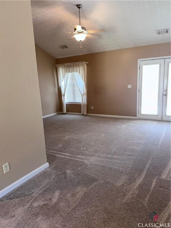 empty room with visible vents, a ceiling fan, baseboards, and carpet floors
