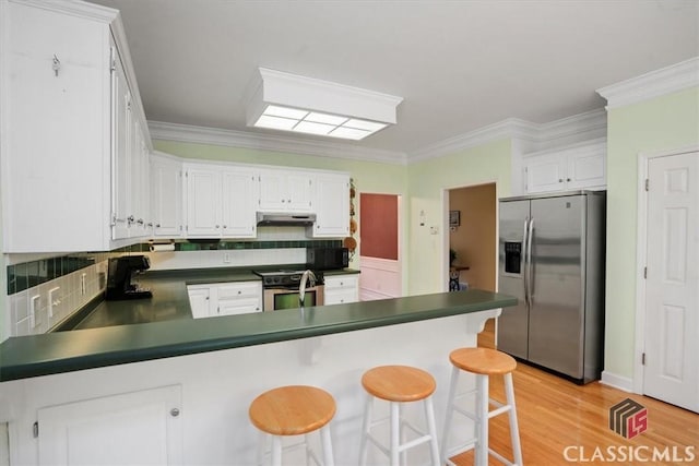 1130 Latham Dr, Watkinsville, GA 30677 - kitchen with appliances with stainless steel finishes, under cabinet range hood, a peninsula, dark countertops, and backsplash