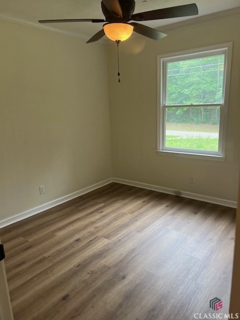 unfurnished room with crown molding, a ceiling fan, baseboards, and wood finished floors