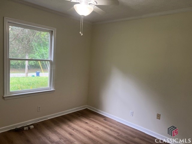 empty room featuring crown molding, baseboards, a ceiling fan, and wood finished floors