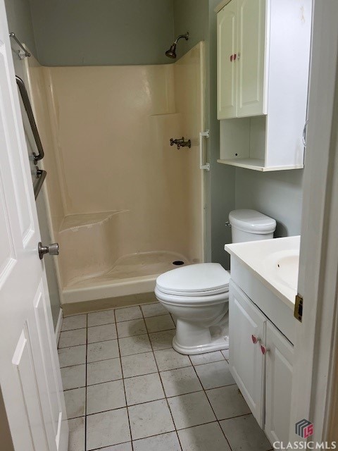 bathroom with toilet, tile patterned floors, a shower stall, and vanity
