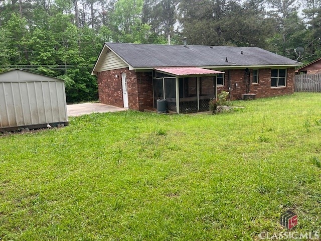 rear view of house with a lawn, an outbuilding, brick siding, fence, and a storage unit