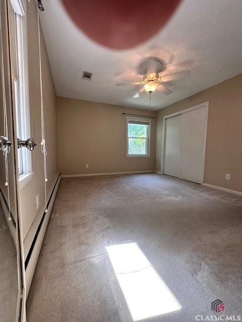 735 Timothy Rd, Athens, GA 30606 - unfurnished bedroom with baseboards, a baseboard heating unit, ceiling fan, visible vents, and light colored carpet