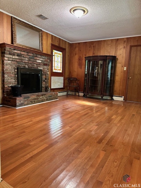 735 Timothy Rd, Athens, GA 30606 - unfurnished living room with a textured ceiling, visible vents, a brick fireplace, wood walls, and wood finished floors