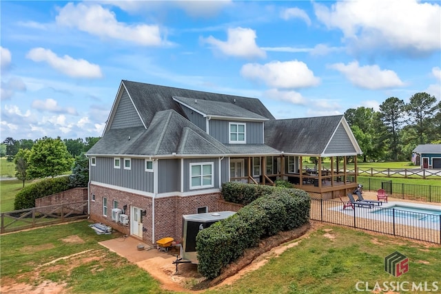 back of house featuring a fenced backyard, board and batten siding, a fenced in pool, and a lawn