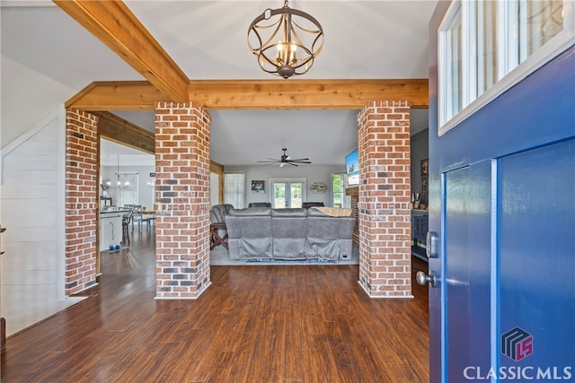 unfurnished living room featuring beamed ceiling, ceiling fan with notable chandelier, ornate columns, and wood finished floors