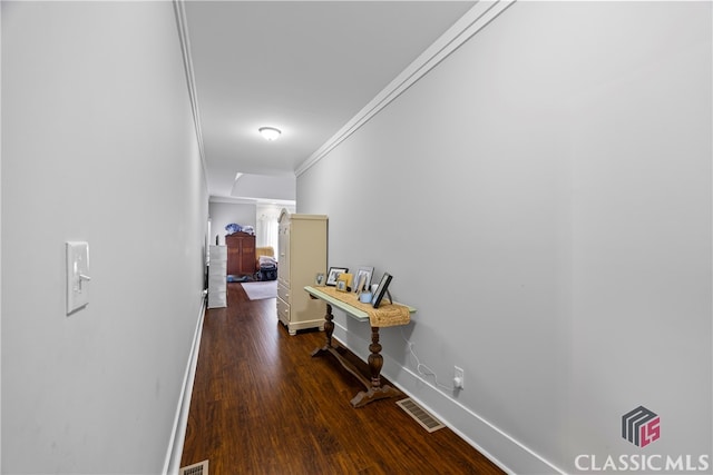 hall featuring baseboards, visible vents, crown molding, and wood finished floors