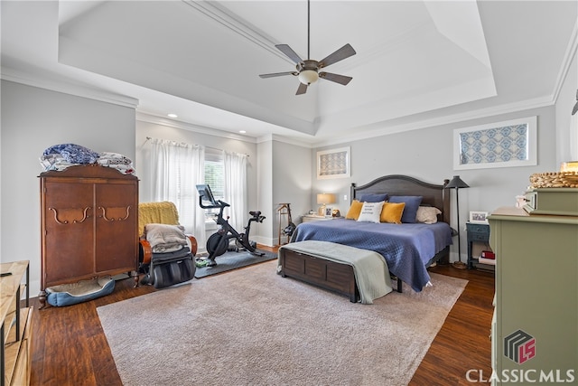 bedroom with a tray ceiling, crown molding, wood finished floors, and a ceiling fan