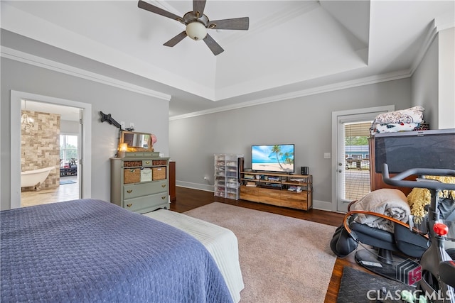bedroom featuring multiple windows, access to outside, a tray ceiling, and wood finished floors