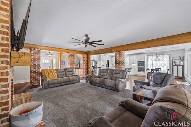 living room with decorative columns, wood finished floors, baseboards, and ceiling fan with notable chandelier