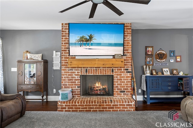 living area featuring a ceiling fan, a brick fireplace, baseboards, and wood finished floors