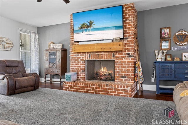 living room featuring a brick fireplace, baseboards, a ceiling fan, and wood finished floors