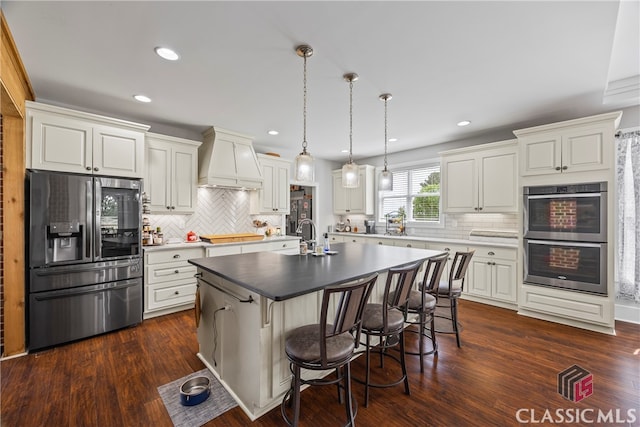 kitchen with a breakfast bar area, backsplash, custom range hood, and appliances with stainless steel finishes