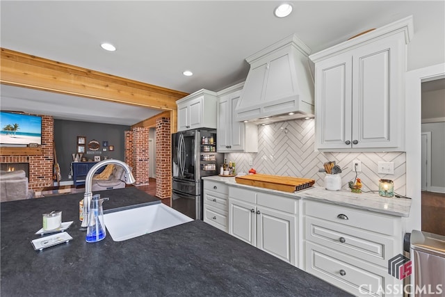 kitchen featuring a sink, smart refrigerator, white cabinetry, stovetop, and custom range hood