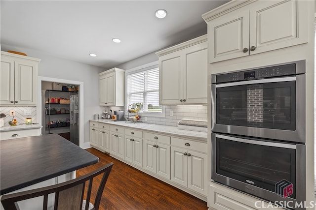 kitchen with light stone countertops, recessed lighting, backsplash, stainless steel appliances, and dark wood-style floors
